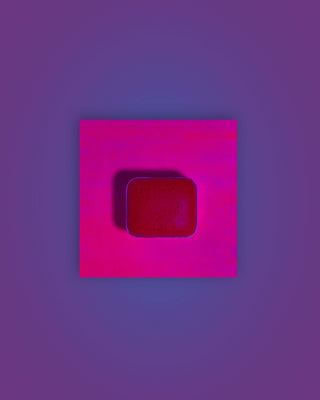 Acuarela individual fluorescente Fucsia en halfpan mostrando su reacción bajo luz UV sobre fondo blanco