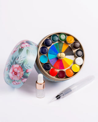 Lata floreada redonda de acuarelas abierta con gotero y pincel